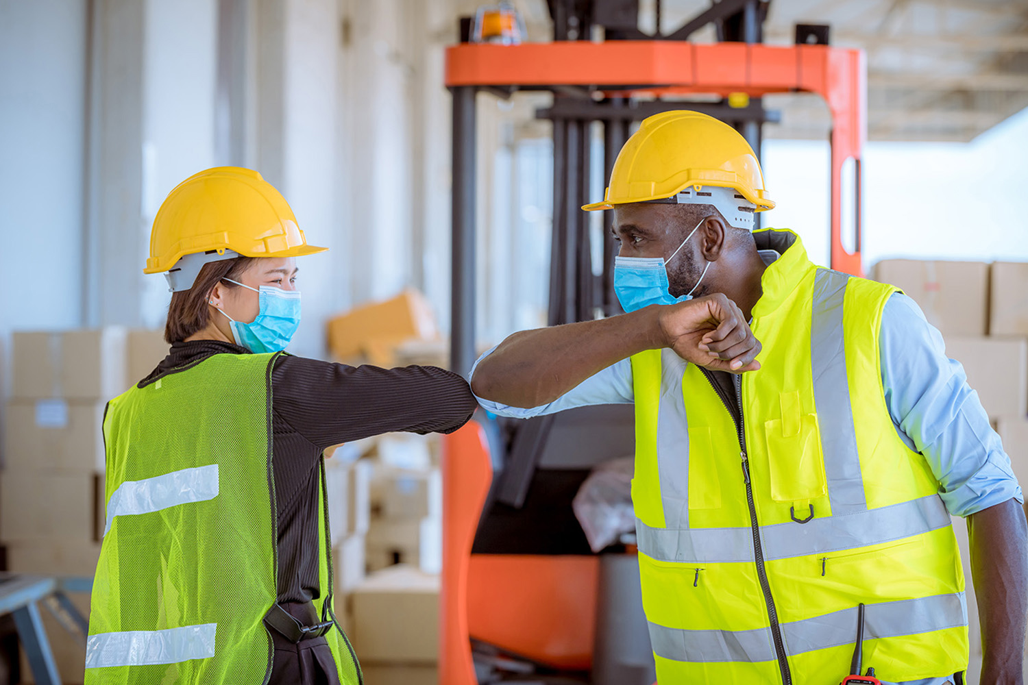 two workers tapping elbows with masks on